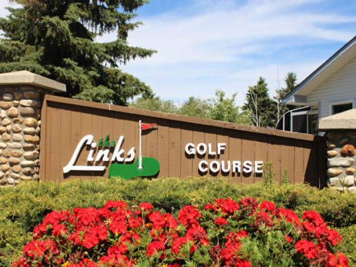 The Links at Spruce Grove sign lined with landscaping and red flowers